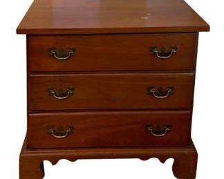 150 - 3-Drawer Nightstand 25.25"x25"x18" (Description): A three-drawer nightstand featuring traditional styling with bracket feet and brass bail pull hardware. The piece is constructed in a warm wood finish. Measures 25.25 inches high by 25 inches wide by 18 inches deep.