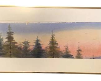 407 - Framed Watercolor Landscape Signed 18.25x37 (Description): A framed watercolor painting depicting a serene lakeside landscape with evergreen trees reflected in calm water. The scene captures soft atmospheric tones of pink, lavender, and blue suggesting either dawn or dusk lighting. The artwork is signed by the artist and features deckled edges on the paper. Presented with cream matting in a gold-tone metal frame. Measures 18.25" x 37.5".