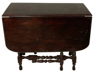 462 - Vtg Drop-Side Gateleg Table 30"x36"x49.5" (Description): Vintage drop-side gateleg table featuring a dark mahogany finish with a rectangular center section and rounded drop leaves. The table is supported by turned legs connected by decorative turned stretchers in a gate-leg style design. The piece shows wear consistent with age, including surface scratching and finish loss on the leaves. Measures 30" x 36" x 49.5".