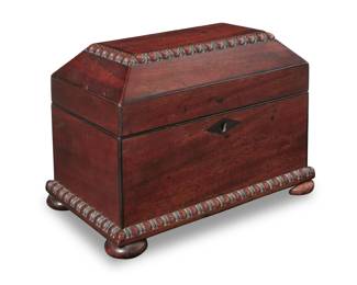 1124 A Regency mahogany tea caddy Early 19th century The casket with gadrooned trimming and locking lid, opening to reveal a velvet lined recess and an inner lidded tea compartment housing a later Toscany Romania glass beaker 6.75" H x 9.25" W x 5.875" D Estimate: $400 - $600