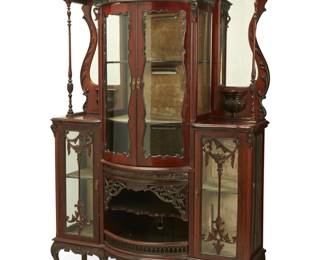 1159 An Edwardian carved mahogany étagère cabinet Early 20th century The carved mahogany vitrine with illuminated and fabric-lined glazed cabinets, adorned with carved panels, foliate openwork, half-urn and garland accents, and carved foliate trimming, featuring a central barrel-front cabinet with single shelf above an open cabinet with single shelf and openwork gallery, all centering two upper mirrors, turned standards, and two smaller opposed glazed cabinets, electrified 86" H x 55" W x 24" D Estimate: $700 - $900