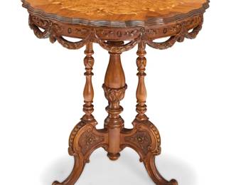 1189 An Italian inlaid carved wood side table 20th century The inlaid top with piecrust edge, burlwood veneer, and floral motif inlay, possibly married to turned supports and elaborately carved tripod legs with scroll feet 29" H x 26.25" Dia. Estimate: $200 - $400