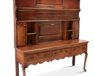 1160 A George III oak Welsh dresser Late 18th/early 19th century The upper section with two dish racks above display niches centering opposed hinged locking cabinet doors, each revealing three small shelves, the lower section with three locking drawers raised on front cabriole legs and rear casters 2 pieces Upper console: 49" H x 76.5" W x 7" D; Lower console: 33" H x 75" W x 19.5" D Estimate: $500 - $700