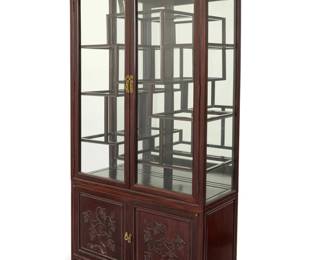1314 A Chinese carved wood display cabinet 20th century The glazed cabinet above a lower console, the doors carved with grapevine motifs, opening to reveal a single shelf 2 pieces Overall: 78" H x 40.5" W x 14.25" D; Upper console: 53.5" H; Lower: 24" H Estimate: $500 - $700