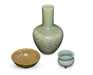 1269 A group of Chinese style celadon porcelain vessels 20th/21st century Vase with indecipherable impressed marks and signature Comprising a vase with foliate scroll motif in low relief, a footed lotus bowl, and a small vessel raised on tripod feet 3 pieces Vase: 11.75" H x 7.375" Dia.; Smallest: 3.25" H x 3.875" Dia. Estimate: $300 - $500