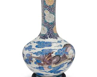 1321 An East Asian polychrome porcelain vase 20th century The stick-neck enameled vase depicting floral motifs to neck above a dragon within clouds to the body, raised on a carved wood stand Vase: 18.75" H x 10.5" Dia.; Stand: 1.75" H x 7.875" Dia. Estimate: $100 - $150