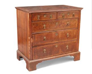 1121 A George I walnut chest Early 18th century The chest with five locking drawers with burlwood fronts and later brass hardware, raised on bracket feet 35.25" H x 37.5" W x 22" D Estimate: $200 - $300