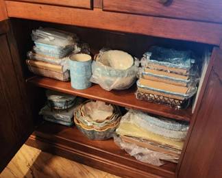 Small accent cabinet filled with bakeware, casserole dishes, pie plates, utensil canisters