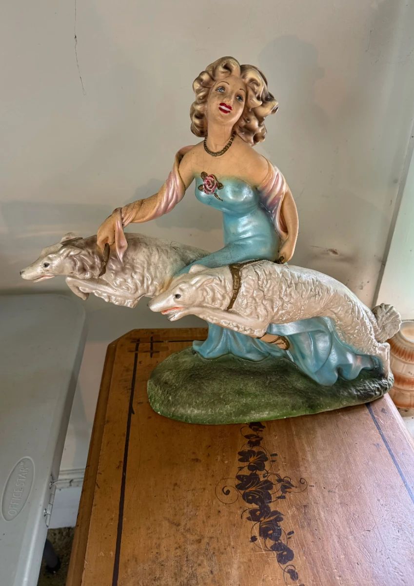 This vintage mid-century chalkware sculpture captures an elegant woman strolling with her graceful Borzoi dogs in true Art Deco style. It’s the kind of piece that instantly sparks conversation and brings a touch of old-world charm to any collection.