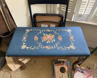 This beautiful vintage needlepoint vanity bench features a stunning blue floral tapestry seat paired with ornately carved wooden legs. Originally designed to tuck beneath a bedroom vanity or dressing table, benches like this were also used with writing desks and even pianos.