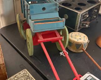 Handcrafted wooden farm wagon featuring a blue slatted bed, bright red chassis, and four green wheels. Includes the front pull shafts. Shows a wonderful, authentic aged patina.