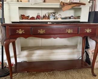 This handsome wooden console table features a classic design that adds warmth and traditional elegance to an entryway, hallway, or living space