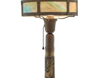 2098 A WWI Trench Art table lamp Early/mid-20th century The single-light lamp with brass and slag glass shade above an artillery shall brass chinoiserie-decorated standard depicting a dragon, electrified 15" H x 9.25" Dia. Estimate: $300 - $500
