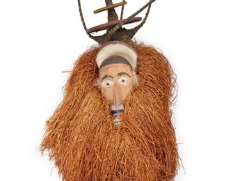 2033 A Yaka Ndeemba polychrome mask Late 19th/early 20th century; Democratic Republic of the Congo The painted carved wood mask with applied raffia, surmounted by a fabric and armature headpiece painted in checkered motifs Overall: 29" H x 17" W x 12" D Estimate: $100 - $200