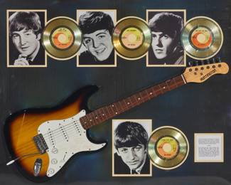 2209 A framed collection of Beatles memorabilia Late 20th century Comprising a replica guitar with etched representations of signatures from the four members of the Beatles, as well as photographic prints and gold-toned reproductions of 7" records from four hit singles Overall: 35" H x 43" W x 5" D Estimate: $500 - $700
