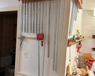 Rack of Bessey parallel bar clamps