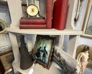 Cute corner shelf featuring beautiful, framed artwork, books, and collectibles