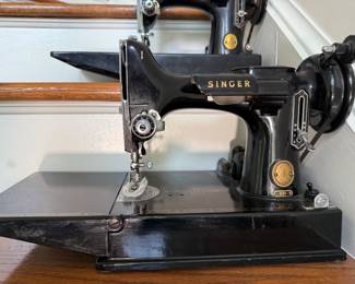Vintage Singer Featherweight 221 sewing machine, recognized by its portable design and black finish with gold decals
