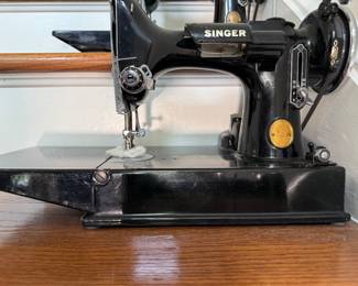 Vintage Singer Featherweight 221 sewing machine, recognized by its portable design and black finish with gold decals