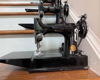 Vintage Singer Featherweight 221 sewing machine, recognized by its portable design and black finish with gold decals