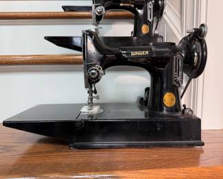 Vintage Singer Featherweight 221 sewing machine, recognized by its portable design and black finish with gold decals