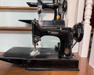 Vintage Singer Featherweight 221 sewing machine features a classic black finish with distinct gold-colored decals
