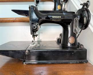 Vintage Singer Featherweight 221 sewing machine, recognized by its portable design and black finish with gold decals