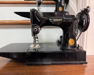 Vintage Singer Featherweight 221 sewing machine, recognized by its portable design and black finish with gold decals