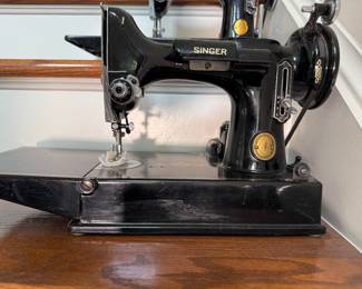 Vintage Singer Featherweight 221 sewing machine, recognized by its portable design and black finish with gold decals