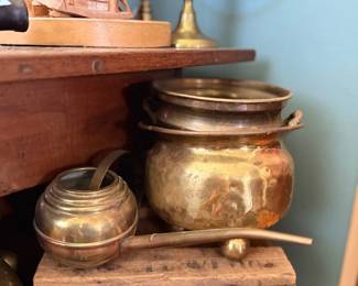 Antique brass pots and carved wood shelf display