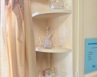 Cut glass decanter and crystal barware in corner cabinet