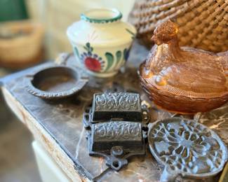 Cast iron trivets, butter molds, and pink glass hen dish