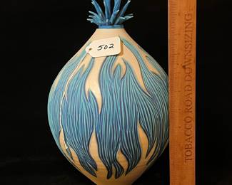A502 - $100. Natalie Blake. Clay Vase with Blue Floral Flower Top. Measures 8" x 12.25" tall. Some flower tips have been repaired