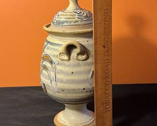 A498 - $30. Brown and Blue Floral Footed Lidded Canister Jar Urn. Signed Don. Measures 5.5" x 11.75" tall. 