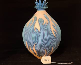 A502 - $100. Natalie Blake. Clay Vase with Blue Floral Flower Top. Measures 8" x 12.25" tall. Some flower tips have been repaired.