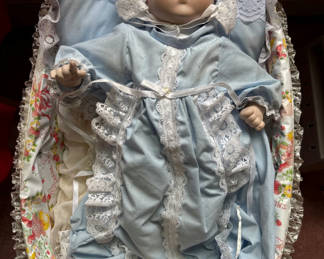 Lot 140: Porcelain baby doll in blue lace-trimmed gown in wicker cradle