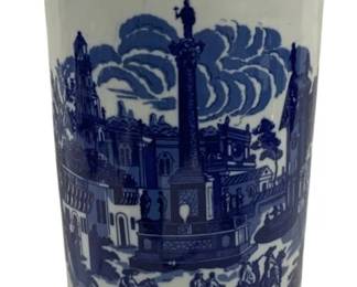 1500 - Blue & White Transferware Umbrella Stand (Description): Blue and white ceramic umbrella stand  featuring transferware decoration with scenic  vignettes depicting classical European town  squares, figures on horseback, architectural  elements, and a central monument column. The upper and lower bands display decorative  cartouches with buildings and pastoral  scenes. Measures 17.5 inches tall by 7.5  inches in diameter.