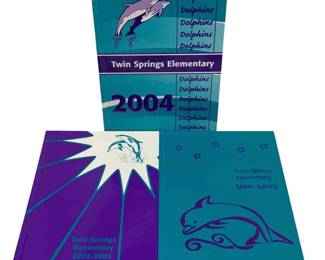 1563 - 3pc Twin Springs Elementary Yearbooks 2002-05 (Description): Collection of three Twin Springs Elementary  School yearbooks spanning the years  2002-2005. The set includes yearbooks from  the 2002-2003, 2004, and 2004-2005 school  years. Each yearbook features the school's Dolphins mascot on the cover in teal  andpurple color schemes. The hardcover  yearbooks are in good condition and document  student life at Twin Springs Elementary  during the early 2000s.