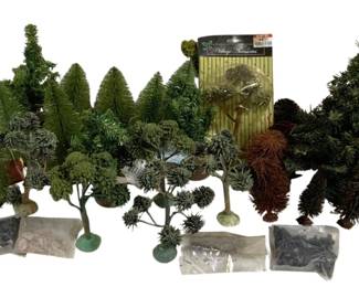 1681 - Lot HO Scale Model Trees & Landscape Scenery (Description): A collection of HO scale tree decorations and  landscape scenery items for model railroads  or holiday village displays. The lot includes  a variety of miniature trees in different  styles and sizes, from bottle brush evergreens to deciduous trees with green  foliage. Also included are bags of  landscaping materials and a packaged Village  Treasures accessory set. Ideal for creating  realistic terrain on model train layouts or