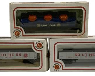 1620 - 3pc Lot Bachmann HO Scale Train Cars (Description): A lot of three Bachmann HO scale train cars  in original boxes. The collection includes  two Southern Railway gondola cars in gray  livery and one Union 76 tank car in blue with  orange dome tops. All cars retain their original Bachmann branded packaging.