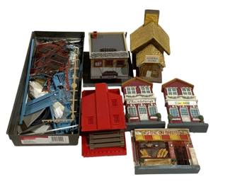 1707 - Assorted Model Train Buildings & Accessories (Description): Assorted model train layout buildings and  accessories. The lot includes several painted  building facades and structures such as a  General Store, Shine On Bakery,  Chuckleberry's Pizza, and a Booker building. Also included is a red plastic building kit  with components, a gold-roofed church or  chapel structure, and a box of assorted blue  and brown plastic model train layout  accessories and parts. Ideal for HO or