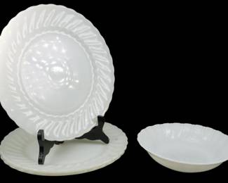 933 - 4 Anchor Hocking Suburbia Milk Glass Pieces (Description): A set of four Anchor Hocking Suburbia pattern  pieces in white milk glass. The lot includes  two dinner plates and a bowl, all featuring  the distinctive swirled rim design  characteristic of the Suburbia line. The pieces display the classic opaque white  finish associated with mid-century milk glass  tableware.