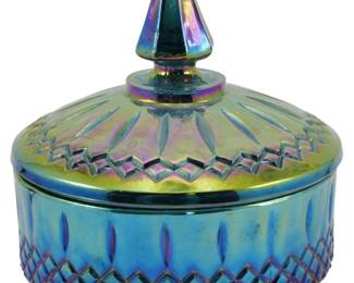 681 - Indiana Electric Blue Princess Carnival Dish (Description): Vintage Indiana Electric Blue Princess Blue  Carnival Glass dish featuring an iridescent  finish with striking blue and purple hues.  The covered dish displays a decorative  diamond pattern around the base, elongated oval motifs on the body, and a radiating  sunburst design on the lid topped with a  pointed finial. The carnival glass exhibits  the characteristic rainbow iridescence  typical of this collectible glassware style.