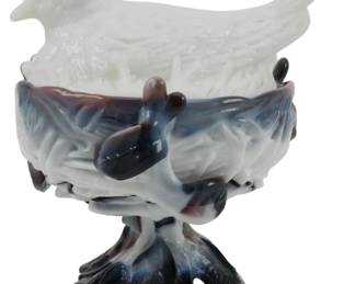 843 - Westmoreland Hen on Nest Purple Slag Glass (Description): Vintage Westmoreland hen on nest in purple  slag glass. The piece features a white milk  glass hen lid resting atop a nest-shaped base  in marbled purple and white slag glass. The  base is supported by a decorative branch or twig-form pedestal in matching purple slag.  Measures 6.5 inches.