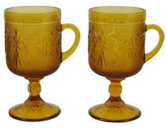 1064 - 4 Vtg Indiana Tiara Sandwich Footed Mugs (Description): Set of four vintage Indiana Glass Tiara  Sandwich pattern footed mugs in amber glass.  Each mug features the classic pressed glass  sandwich pattern with floral and scroll  designs, a decorative pedestal base, and applied handle. Measures 5.5" tall.