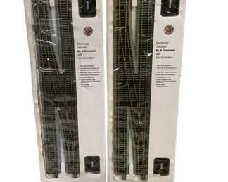 1691 - Bachmann HO Scale Train Track Crossovers Lot (Description): Lot of Bachmann HO Scale train tracks  featuring two boxed Electrically Operated No.  6 Crossovers with two controllers each, part  of the E-Z Track System. The boxes show some  wear and aging. Also included is one loose crossover track section outsideof packaging.  These crossover tracks allow for switching  between parallel tracks in model railroad  layouts.