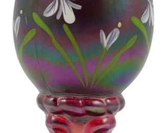 773 - Fenton Handpainted Egg Figure 159/950 4" (Description): Fenton handpainted egg figure, numbered  159/950 in a limited edition series. The  iridescent carnival glass egg features  hand-painted yellow butterflies and white  flowers with green stems against a purple-amethyst backdrop. The egg rests on a  matching red iridescent carnival glass  pedestal base with a ruffled collar design.  Measures 4 inches tall.