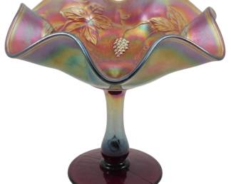 678 - Vtg Fenton Amethyst Grape & Leaves Compote (Description): Vintage Fenton amethyst carnival glass  compote featuring the Grape & Leaves pattern.  The bowl displays a beautiful ruffled edge  with iridescent finish showing rainbow hues  of pink, gold, green, and purple. The pressed glass design showcases grape clusters and  vine leaves. The compote stands on a pedestal  base with deep amethyst coloring. Measures  6" x 6".