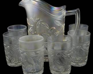 741 - Imperial Clear Iridescent Bird Pitcher Set (Description): Vintage Imperial clear iridescent glass  pitcher set featuring a raised bird and  foliage design. The set includes a pitcher  with a ruffled rim and applied handle,  accompanied by six matching tumblers decorated with the same bird motif in relief.  The glass has a beautiful frosted iridescent  finish that catches the light with rainbow  hues. Pitcher measures 8.5" tall.