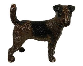 1512 - Cast Iron Dog Terrier Doorstop 8"x8.5"x3.5" (Description): Cast iron dog figure depicting a terrier in a  standing pose with tail raised. The piece  features a dark painted finish with brown and  black coloring showing age-appropriate wear.  Measures 8 inches long by 8.5 inches tall by 3.5 inches wide.